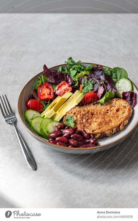 Bowl of green salad with slice of bread tomato food healthy fresh arugula meal diet vegetable vegetarian plate lunch eating leaf nutrition spinach toast veggie