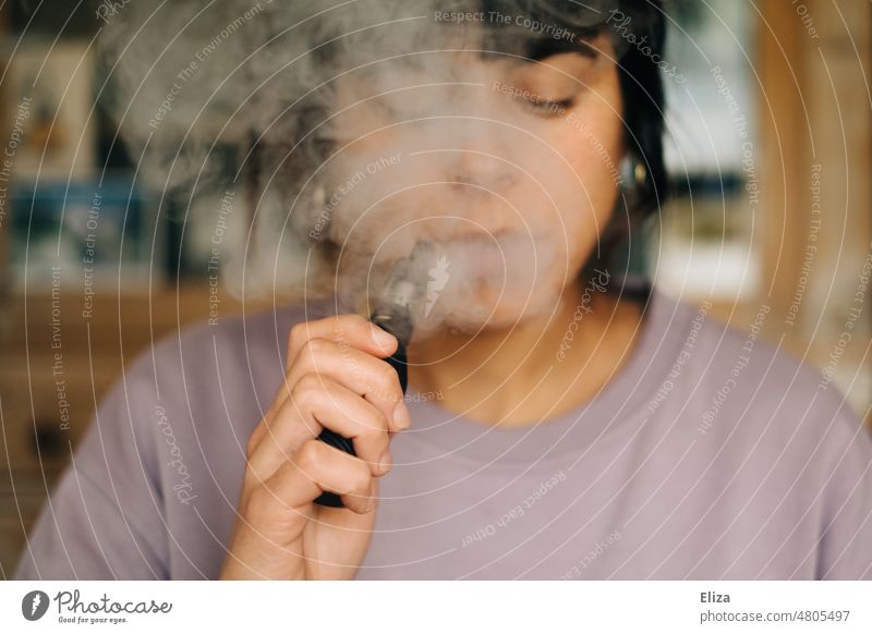 Woman steams an e-cigarette, as an alternative to smoking e-zigarette Evaporator vaping smoking cessation Smoker Nicotine Electric electronic cigarette vapen