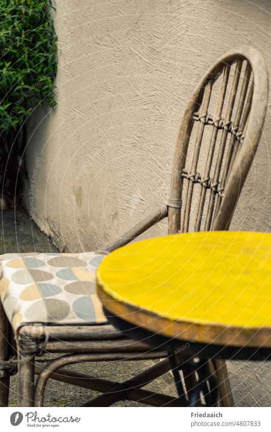 Wooden chair and round table with yellow top on a house wall Table Chair seat Lounges Yellow Cozy Exterior shot Colour photo Seating Furniture Empty Calm