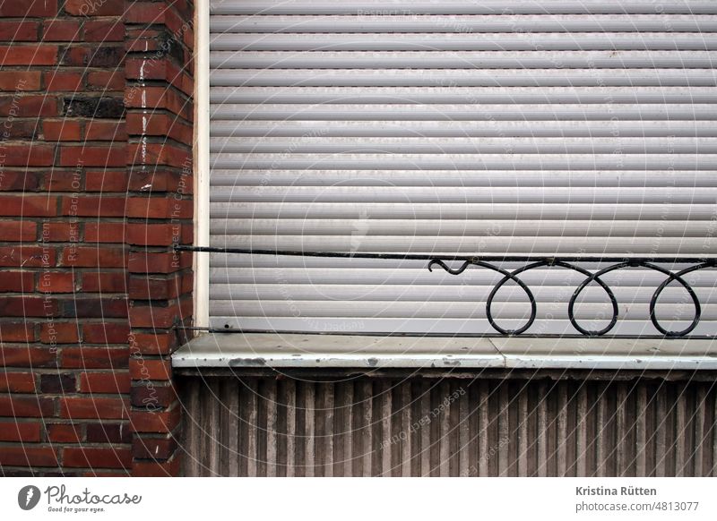 exclamation mark on the brick facade next to a closed roller shutter Window Roller shutter Roller blind Venetian blinds Closed locked too Window board Facade