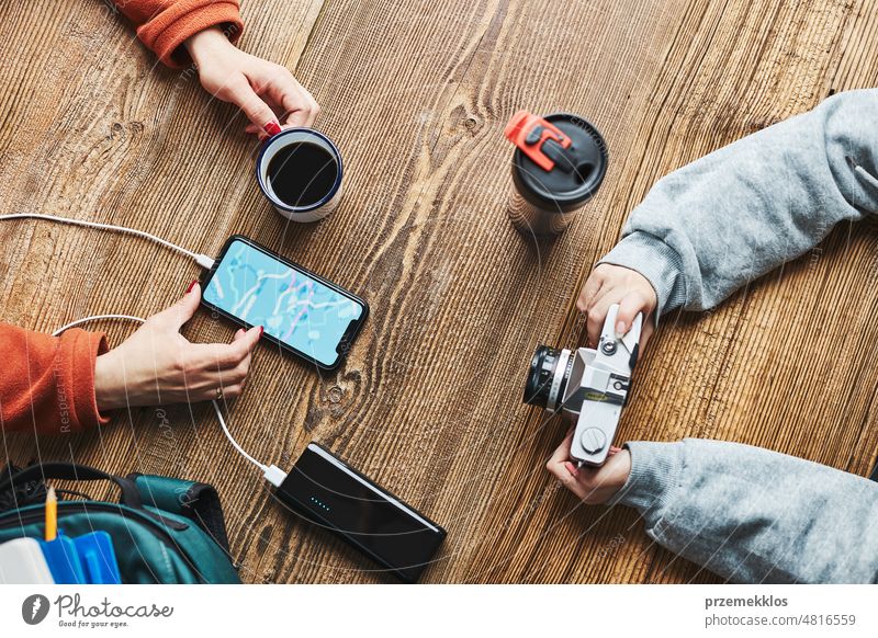 Family planning vacation trip. Woman searching travel destination and routes using navigation map on mobile phone. Charging smartphone with power bank. Using technology while travelling