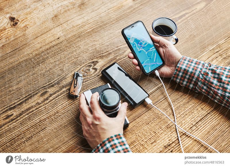 Man planning next vacation trip while journey. Searching travel destination and routes using navigation map on mobile phone. Charging smartphone with power bank. Using technology while travelling