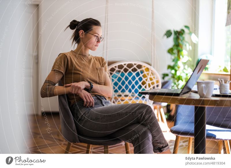 Young woman using a laptop at home domestic life confidence indoors house people young adult casual female Caucasian attractive beautiful tattoos one positive