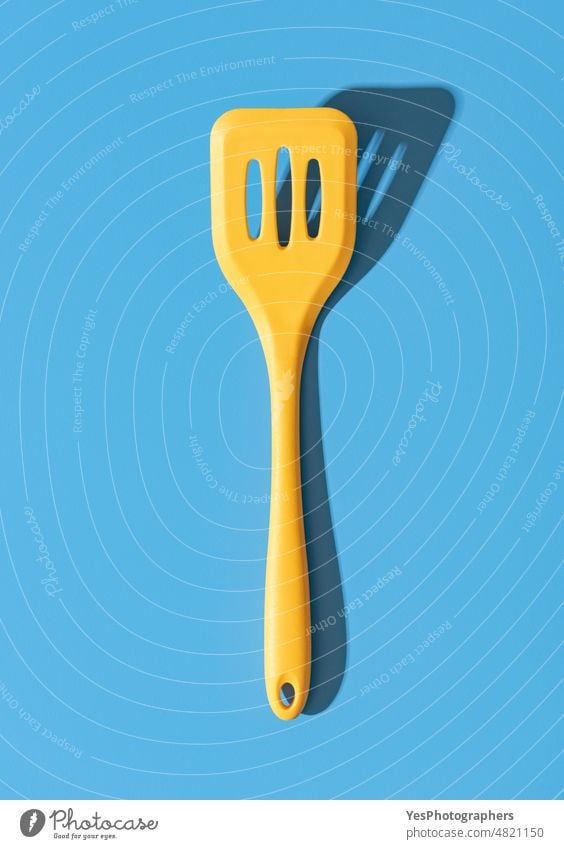 Silicone spatula minimalist on a blue table. Yellow stapula top view. above background bakery blank bright chef close-up color colorful confectionary cooking