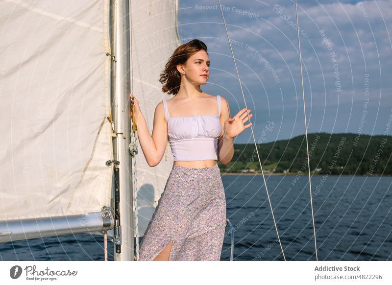 Calm young lady admiring nature while standing on sailboat woman sea yacht admire holiday cruise summer vacation female portrait trendy style trip brown hair
