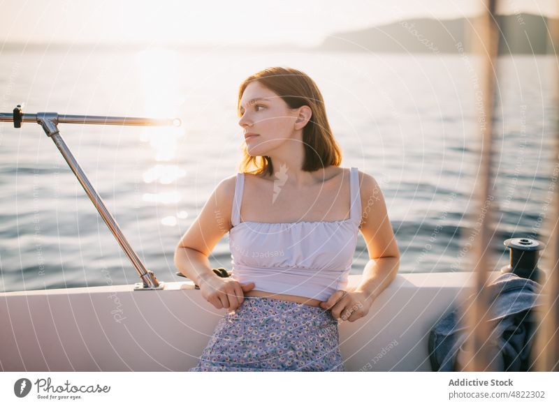 Calm young lady admiring nature while sitting on sailboat woman sea yacht admire holiday cruise summer vacation female portrait trendy style trip brown hair
