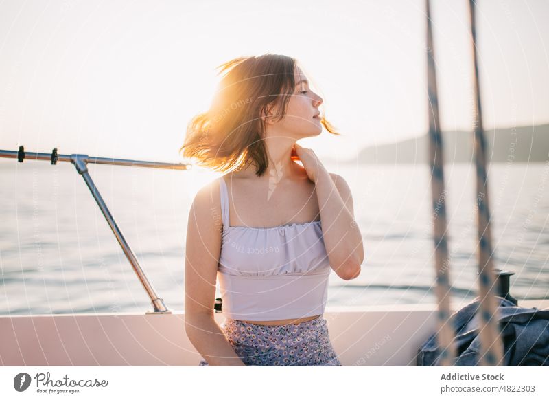 Calm young lady admiring nature while standing on sailboat woman sea yacht admire holiday cruise summer vacation female portrait trendy style trip brown hair