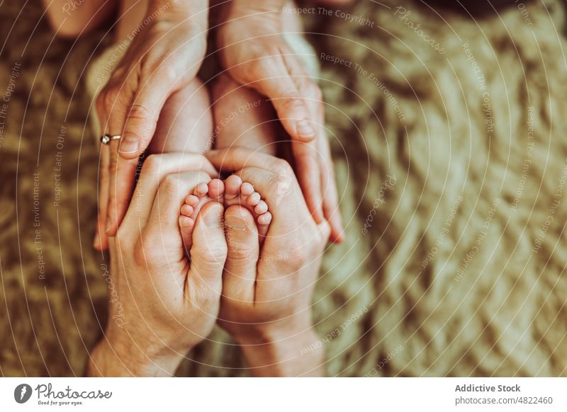 Crop faceless parents touching feet of cute infant family baby mother father caress love hug newborn dad mom generation offspring together barefoot tender