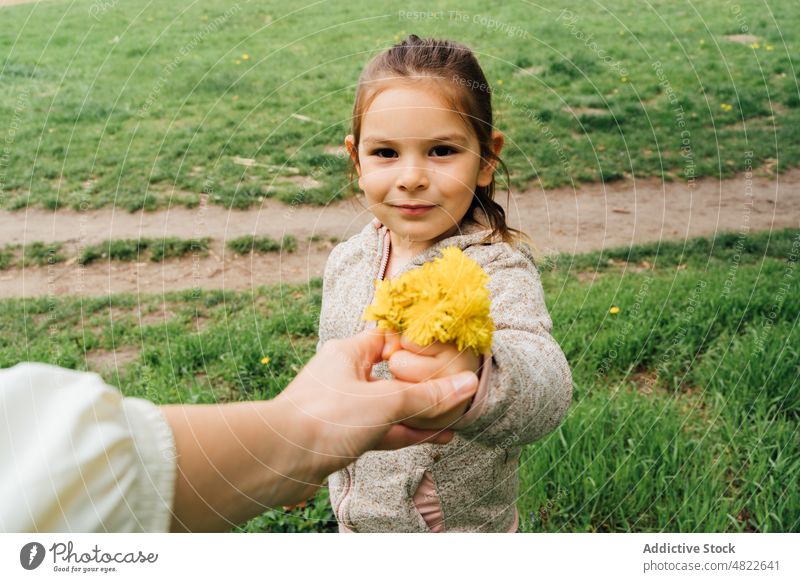 Child giving picked flowers to mom in park woman girl child dandelion present spend time mother together nature gift countryside kid meadow warm clothes spring