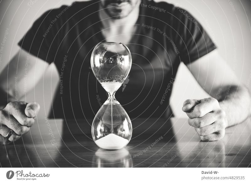 Time is running out - man in front of an hourglass - a Royalty