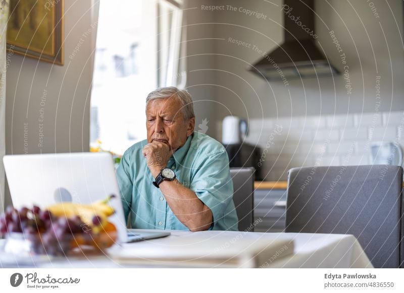 Elderly man using laptop at kitchen table senior adult older aged portrait person casual leisure lifestyle pensioner caucasian retired people mature retirement