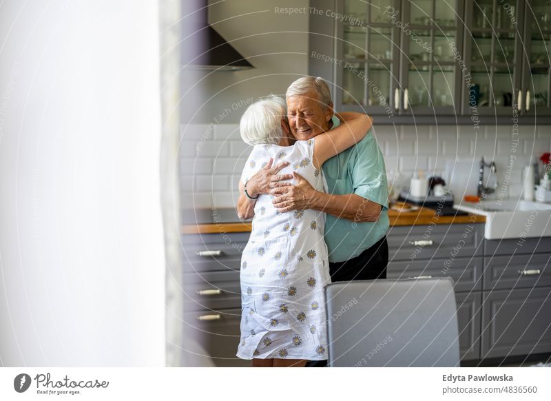 Senior Couple Hugging in their Kitchen senior adult older aged portrait person casual leisure lifestyle pensioner caucasian retired people mature retirement