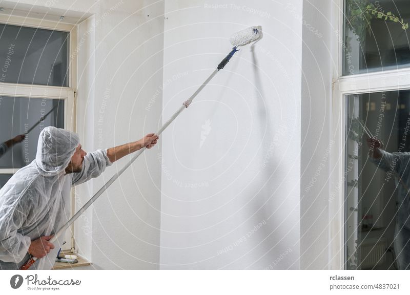 painter working with paint roller to paint the wall of a room. do it yourself concept image arm close up color construction decor creative designer decorating