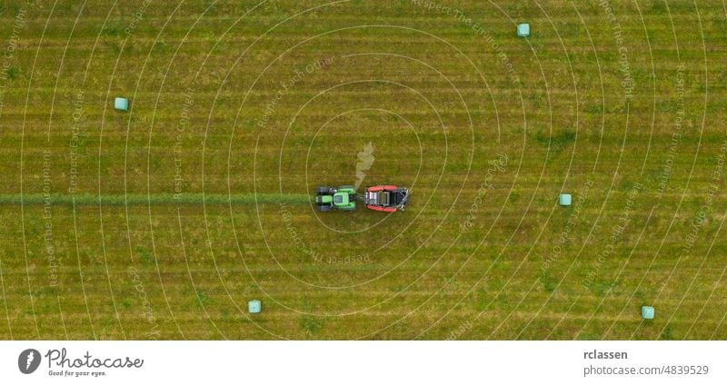 Aerial view of Tractor mowing green field in summer. Drone Shot farm tractor above aerial agricultural agriculture agronomy background bale blue combine country