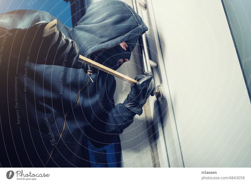 masked burglar opens a door with a crowbar police apartment steal white robbery tool housebreaker concept illegal male insurance glove black theft protection