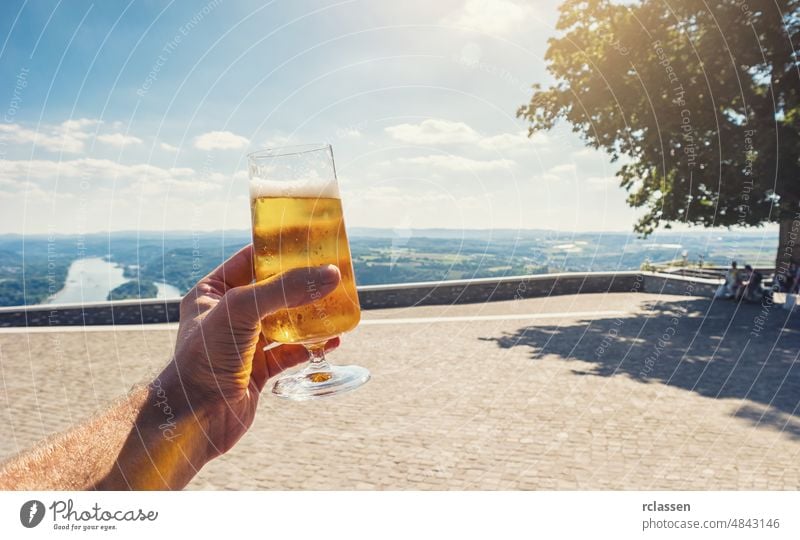 young man drinks fresh beer in a beer garden at summer travel nudge trees bright sunny restaurant germany munich hold tradition pleasure oktoberfest cheers