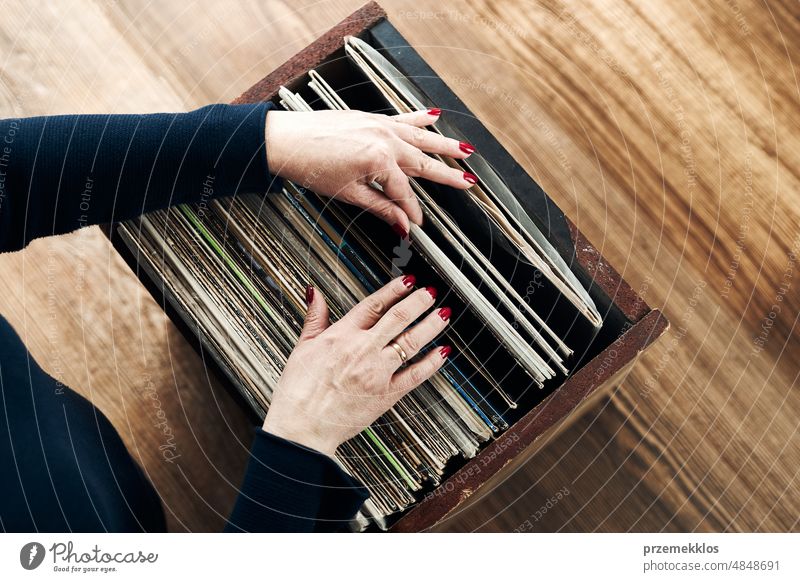 Playing vinyl records. Listening to music from vinyl record player. Retro and vintage music style. Woman holding analog LP record album. Music passion listening