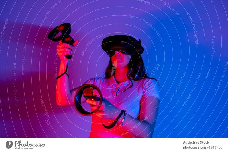 Woman in VR headset playing videogame woman vr cyberspace simulate futuristic virtual reality gamer augmented modern explore neon goggles innovation controller