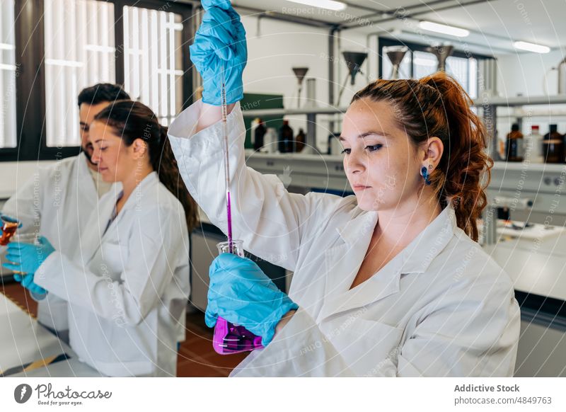 Chemist pouring liquid into flask in lab woman scientist laboratory chemical chemist experiment sample research expertise pharmacy colleague science focus