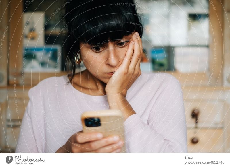 Young woman looks at her smartphone and is worried Shock bad news Frightening Distress Fear Panic Horror Woman Cellphone Scare stock market crash portrait Bad