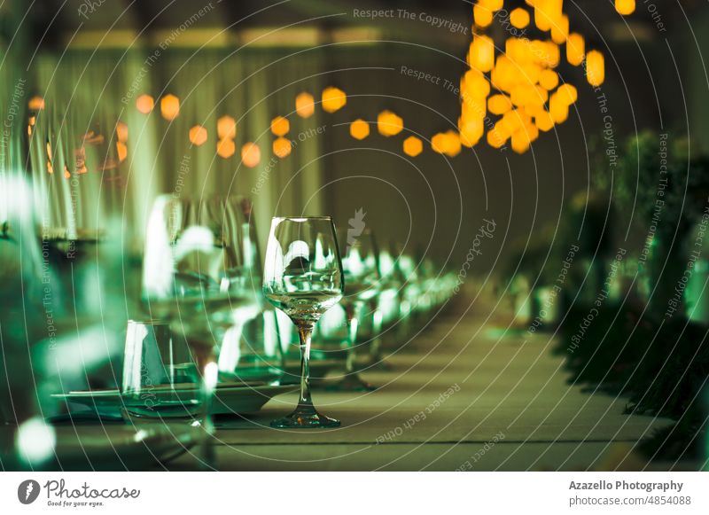 Wedding table view with blurry yellow lights. wine glass champagne feast wedding celebration abstract green shallow depth field focus evening restaurant