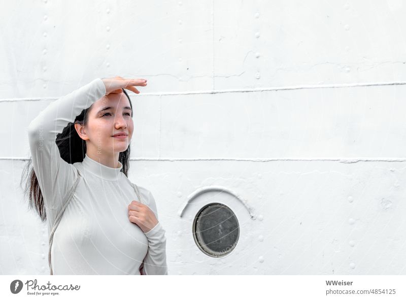 A young woman in white in front of a ship wall looks confidently into the future or just into the distance Woman Girl Future Looking Maritime Navy White Beige