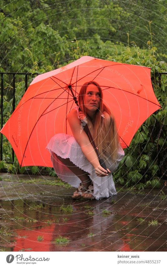 A long haired blonde woman ducks under red umbrella in rainy weather Woman Umbrella Rainy weather Umbrellas & Shades Weather Bad weather Red rain shelter Wet