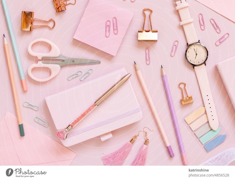 Pink school girly accessories and stationery on pastel pink background Top view education notebook scissors pencils pens sticky note paper clips watch