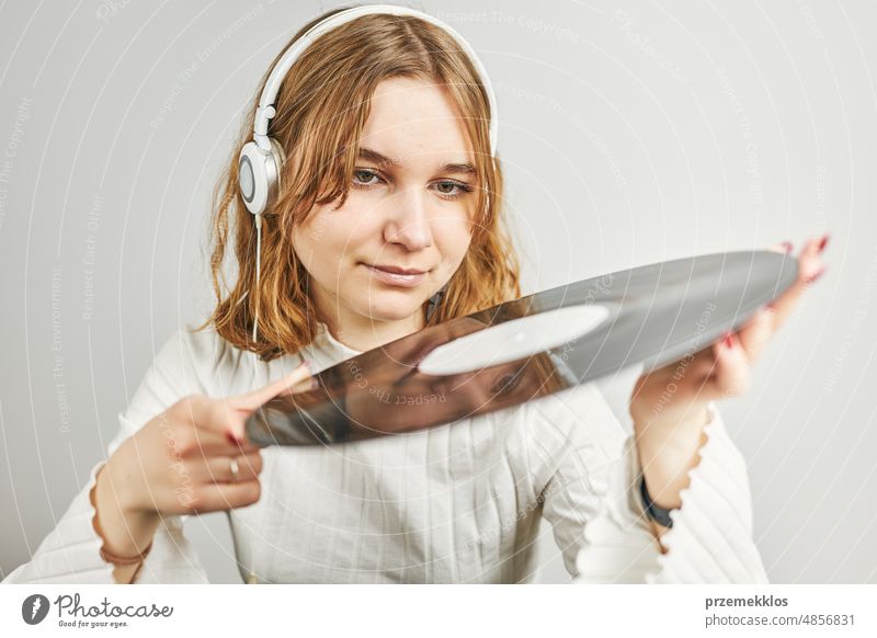 Young woman listening to music from vinyl record player. Playing music on turntable player. Female enjoying music from old record collection at home analog