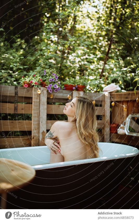 Unrecognizable woman sitting in bathtub water patio skin care terrace wellbeing routine topless chill style appearance rest wash summer charming lady summertime