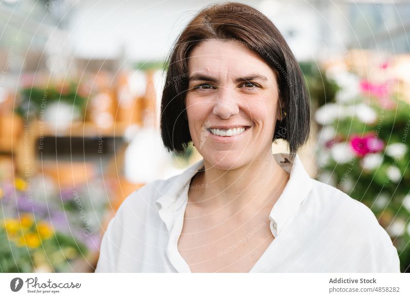 Happy adult woman in flower shop smile happy friendly client seller portrait brunette female cheerful store short hair glad positive dark hair human face