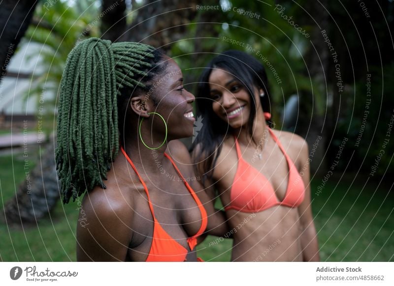 Cheerful black women in swimsuits standing near grove friend bonding bikini tropical leisure pastime spend time backyard swimwear female resort african american