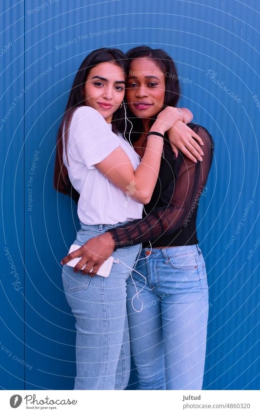 Two friends embrace each other in front of a blue wall. Girl Ethnicity spain Young Woman Twenties Trendy BuildingExterior Girlfriend Friendship Female Friends