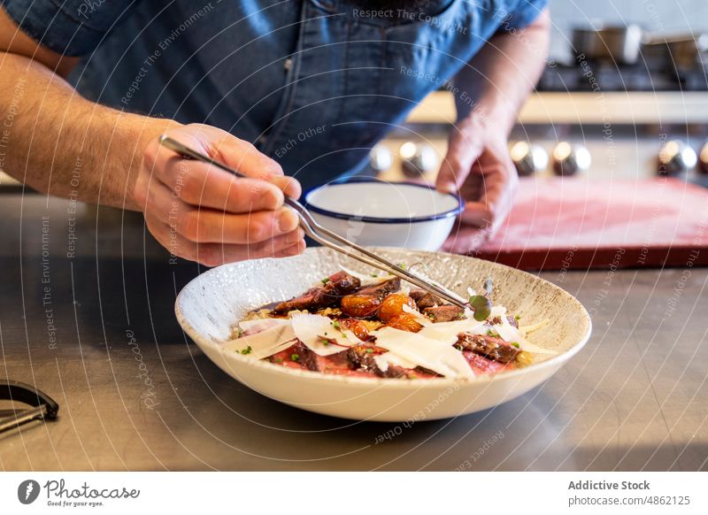 Chef Garnishing Herb On Main Dish In Commercial Kitchen Tweezers Counter Steak Cheese Restaurant Beef Bowl Preparing Finishing Dressing Gourmet Cuisine Lunch