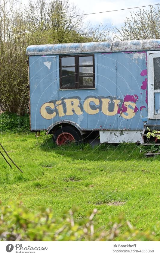 old circus wagon in garden Sunlight Contrast Light Copy Space bottom Colour photo Exterior shot Blue Acrobat Inscription Letters (alphabet) Circus trailer