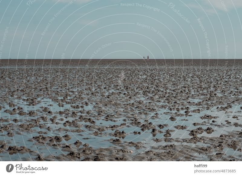 three people at low tide in mudflats with many lugworm piles Summer Island Lugworm pile ebb and flow Slick Mud flats Walk along the tideland coast Ocean