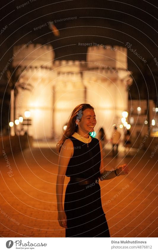 Happy woman walking in the historic center of the city with lights. Smiling happily, going to the party. Young and beautiful female tourist in Spain. happy