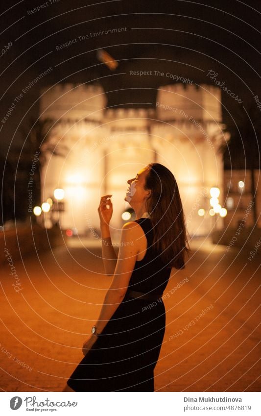 Happy woman walking in the historic center of the city with lights. Smiling happily, going to the party. Young and beautiful female tourist in Spain. happy