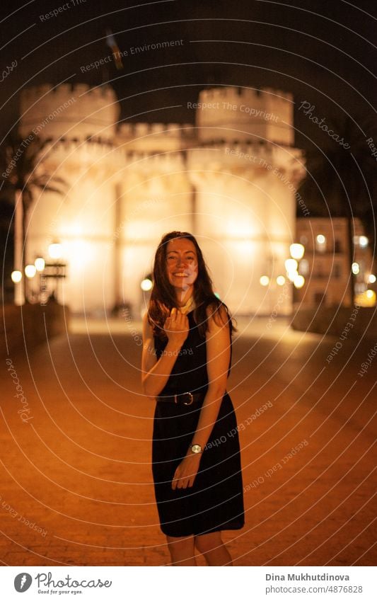 Happy woman walking in the historic center of the city with lights. Smiling happily, going to the party. Young and beautiful female tourist in Spain. happy