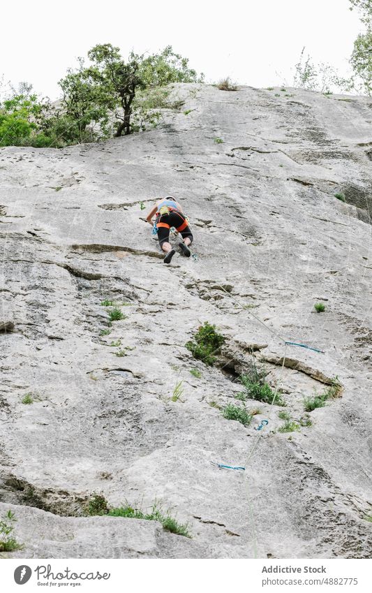 Unrecognizable female climber ascending on cliff in summer Female Hiker Climbing Cliff Rocky Harness Rappel Helmet Adventure Challenge Mountaineering Hiking