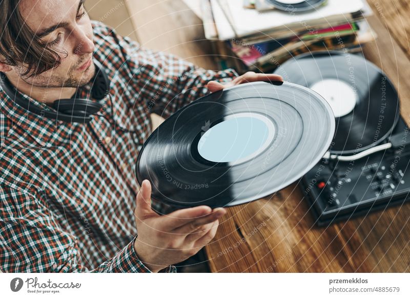 Man listening to music from vinyl record. Playing music from analog disk on turntable player. Enjoying music from old collection. Retro and vintage album retro