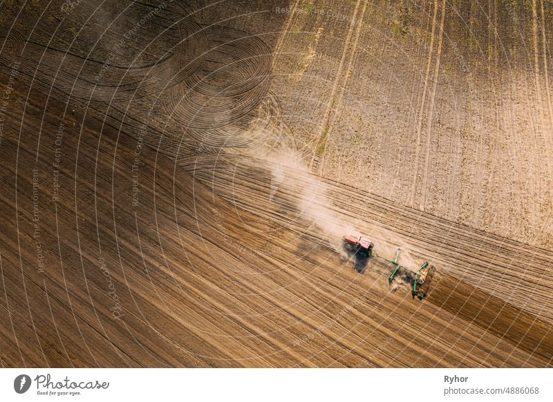 Aerial View. Tractor Plowing Field. Beginning Of Agricultural Spring Season. Cultivator Pulled By A Tractor In Countryside Rural Field Landscape. Dust Rises From Under Plows
