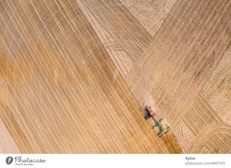 Aerial View. Tractor Plowing Field. Beginning Of Agricultural Spring Season. Cultivator Pulled By A Tractor In Countryside Rural Field Landscape aerial