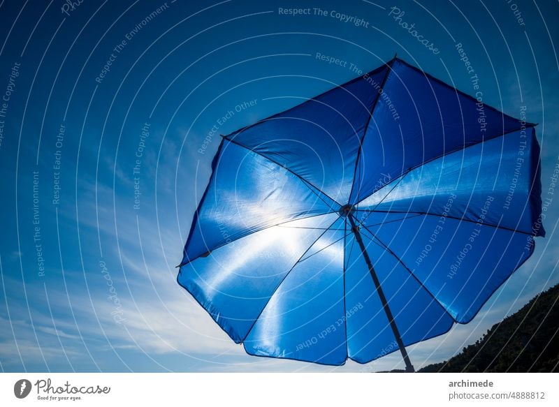 Vibrant blue beach umbrella against sun background burn clear copy space day heat holiday hot nobody object protection sky summer summertime textile vacation