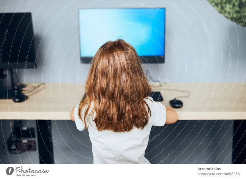 Child learning to use technology in classroom at primary school. Schoolgirl using computer on elementary computer science class. Back to school child e-learning