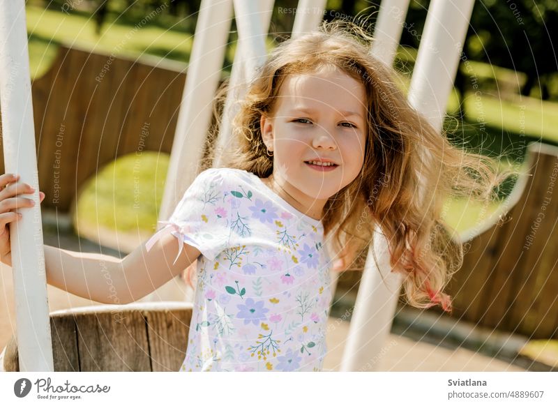 Portrait of a beautiful girl swinging on a swing on a summer day. Childhood, recreation, summer time playground child happiness park fun expressing positivity