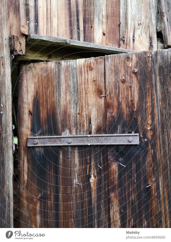 Old stable door made of brown wood with rusty iron on an old farm in Rudersau near Rottenbuch in the district of Weilheim-Schongau in the Pfaffenwinkel in Upper Bavaria