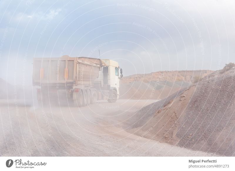 Dump truck entering a quarry to unload gravel, covered in dust. dump truck machine loader digger sand tractor carrier charge earth force power transportation