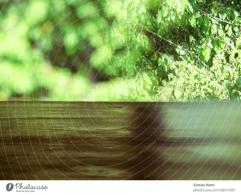 View into the green Wooden table outlook Green bush Light and shadow shade dispenser blurred Depth of field Contrast Shadow Shaft of light Ambience