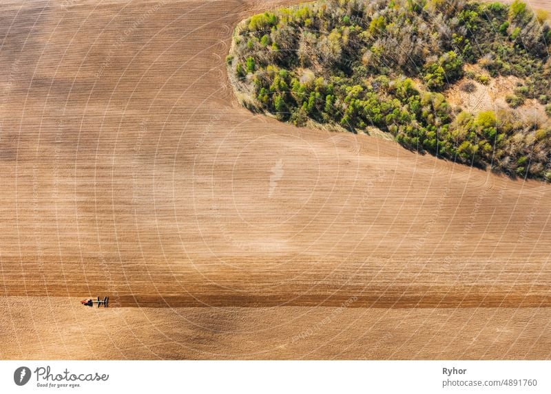 Tractor Plowing Field In Spring. Beginning Of Agricultural Season. Cultivator Pulled By A Tractor In Countryside Rural Field. Countryside Field Landscape. Aerial View. Top Flat View